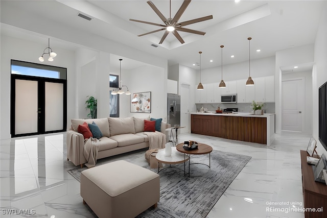 living room featuring ceiling fan with notable chandelier and a tray ceiling