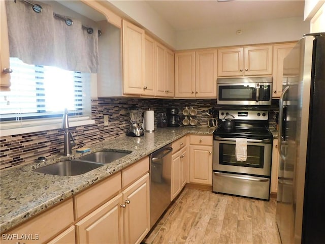 kitchen featuring sink, light wood-type flooring, light brown cabinetry, appliances with stainless steel finishes, and light stone counters