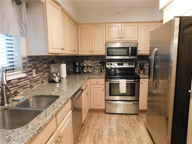 kitchen featuring light brown cabinets, sink, light hardwood / wood-style floors, light stone counters, and stainless steel appliances