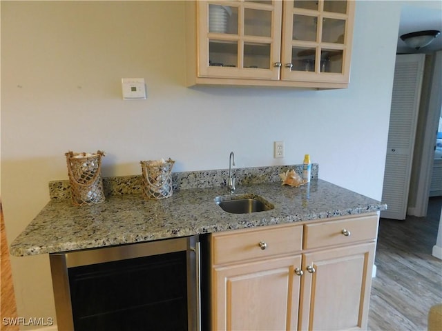 kitchen with light stone countertops, light brown cabinets, beverage cooler, and sink