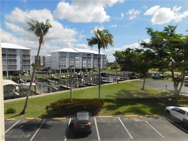 view of vehicle parking with a yard and a water view