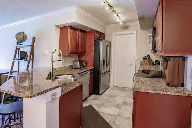 kitchen featuring light stone counters, kitchen peninsula, a textured ceiling, stainless steel appliances, and a breakfast bar