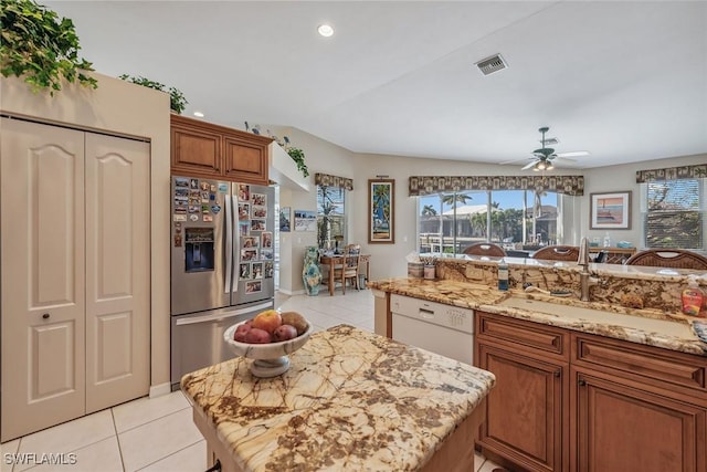 kitchen featuring lofted ceiling, ceiling fan, a kitchen island, stainless steel refrigerator with ice dispenser, and white dishwasher