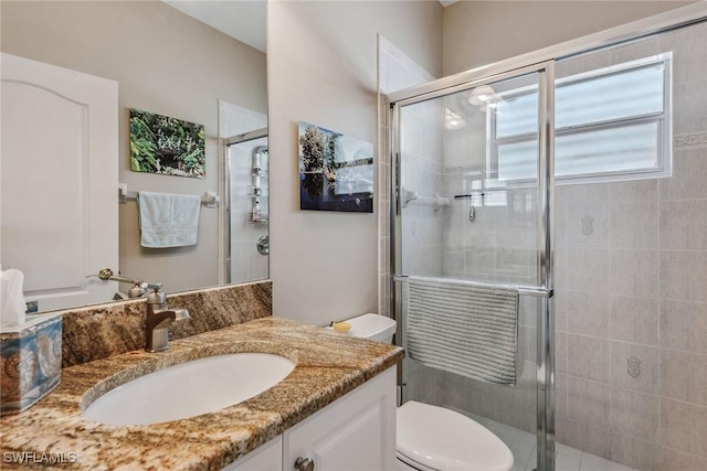 bathroom featuring a shower with door, toilet, and vanity