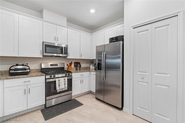 kitchen featuring light stone counters, white cabinets, appliances with stainless steel finishes, and light tile patterned floors