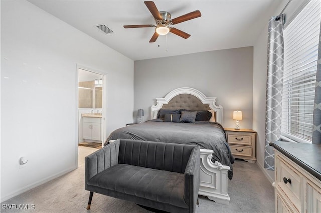 bedroom featuring ceiling fan, ensuite bath, and light colored carpet