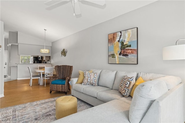 living area featuring ceiling fan, baseboards, vaulted ceiling, and wood finished floors