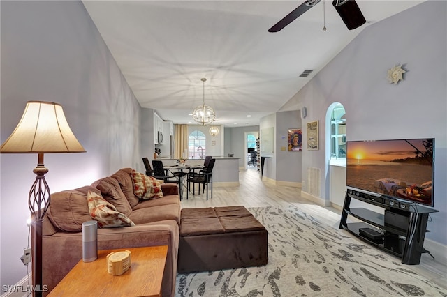 living room featuring lofted ceiling, ceiling fan with notable chandelier, and light hardwood / wood-style flooring