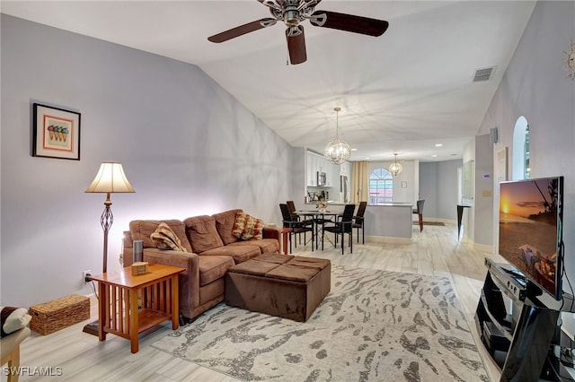 living room featuring ceiling fan with notable chandelier, light hardwood / wood-style flooring, and lofted ceiling