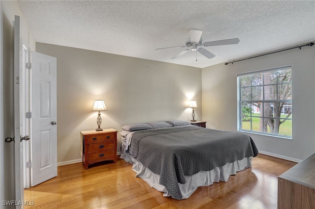 bedroom with ceiling fan, a textured ceiling, and light hardwood / wood-style flooring