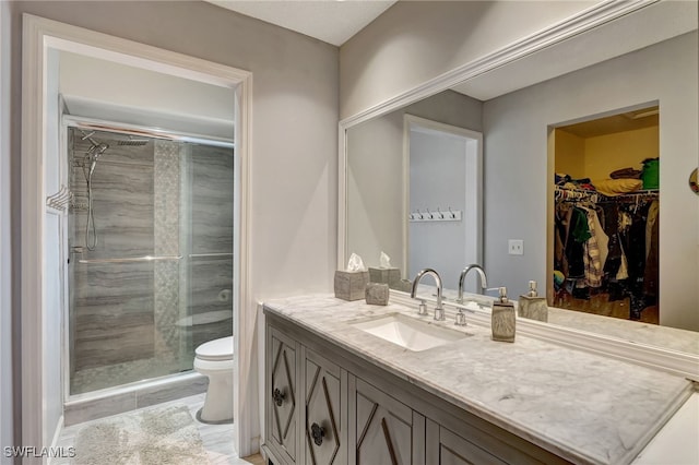 bathroom with toilet, a shower with shower door, and vanity