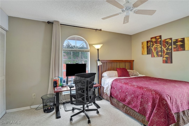 carpeted bedroom with ceiling fan, a closet, and a textured ceiling