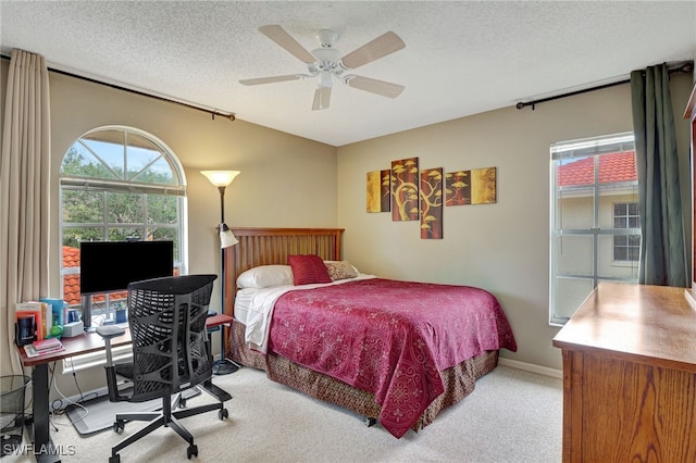 carpeted bedroom with ceiling fan and a textured ceiling