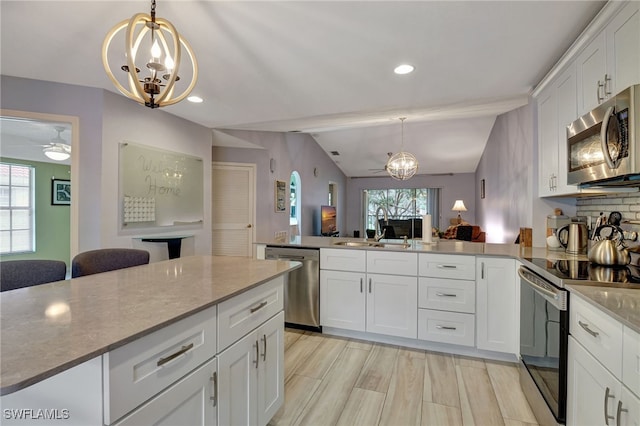 kitchen featuring vaulted ceiling, sink, stainless steel appliances, and white cabinetry