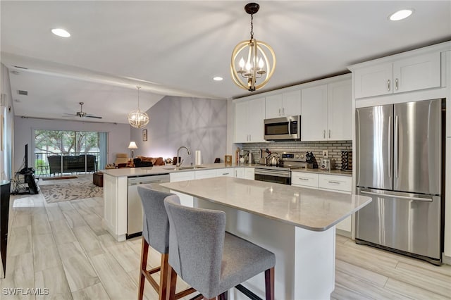 kitchen featuring decorative light fixtures, kitchen peninsula, sink, and stainless steel appliances