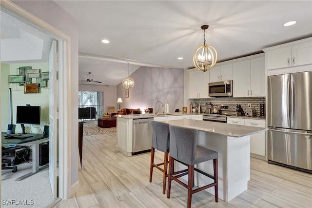 kitchen with white cabinets, appliances with stainless steel finishes, sink, and a center island