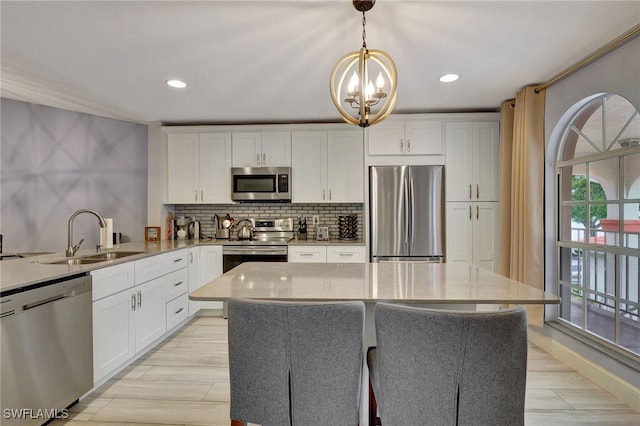 kitchen with appliances with stainless steel finishes, pendant lighting, white cabinetry, and sink