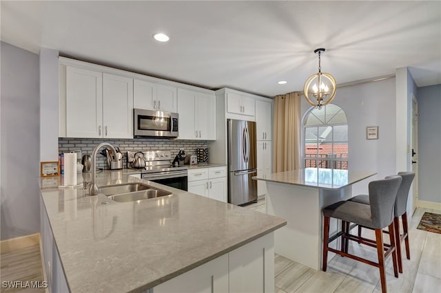 kitchen featuring stainless steel appliances, pendant lighting, white cabinetry, and sink