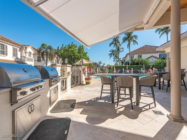 view of patio with a fenced in pool, a grill, and exterior kitchen