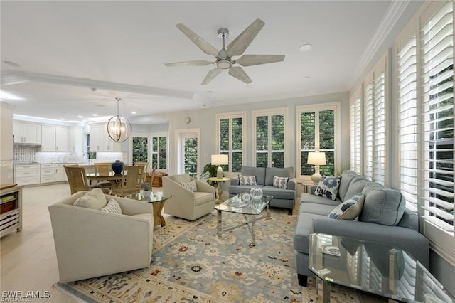 living room with ceiling fan with notable chandelier and ornamental molding