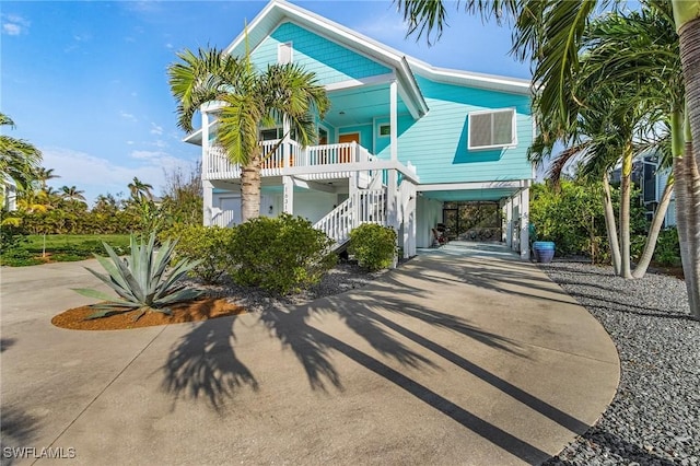 raised beach house featuring a porch and a carport