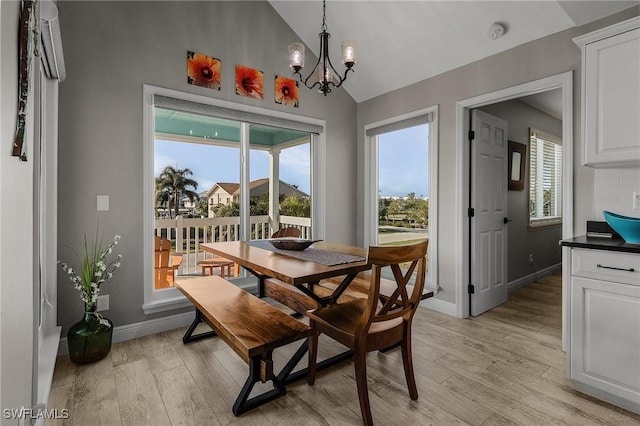 dining area with lofted ceiling, an inviting chandelier, and light wood-type flooring