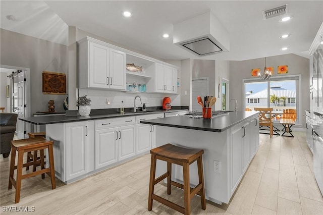 kitchen featuring white cabinets, a kitchen island with sink, a breakfast bar area, and sink