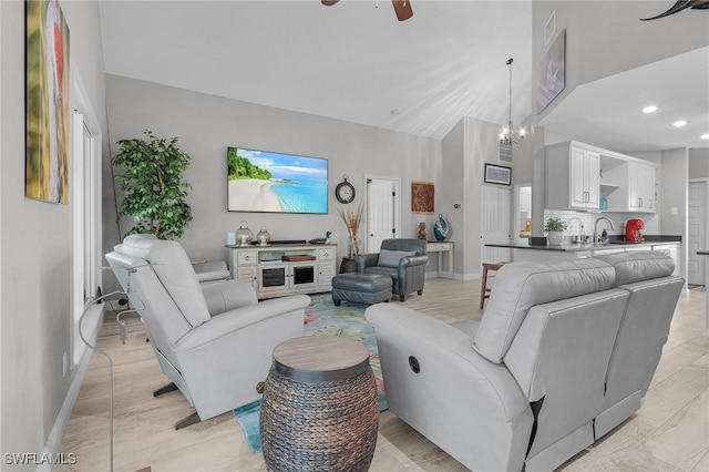 living room featuring sink, ceiling fan with notable chandelier, and vaulted ceiling