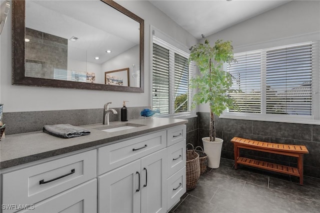 bathroom with lofted ceiling, tile patterned flooring, vanity, and tile walls