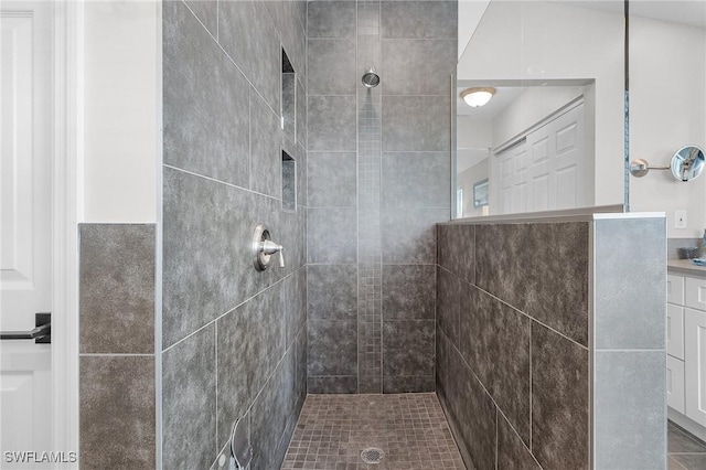 bathroom with a tile shower and vanity