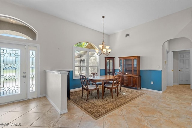 dining area with baseboards, visible vents, arched walkways, and a notable chandelier