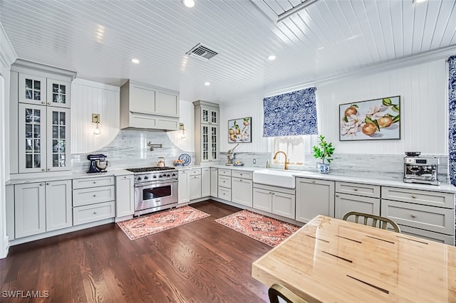 kitchen with sink, dark wood-type flooring, high end range, backsplash, and custom exhaust hood