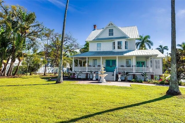 rear view of house featuring covered porch and a lawn