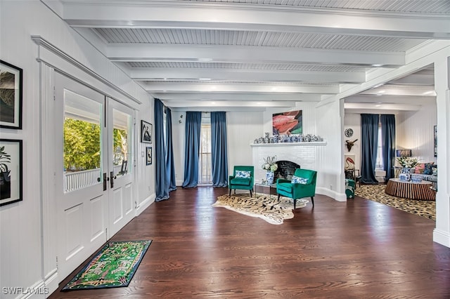 foyer entrance featuring a brick fireplace, beam ceiling, a wealth of natural light, and dark hardwood / wood-style floors