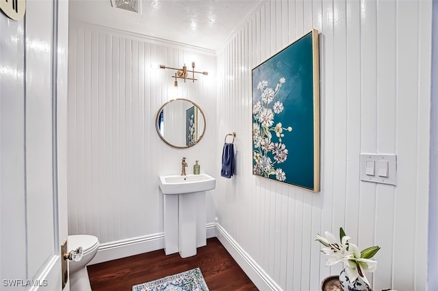 bathroom with ornamental molding, toilet, sink, and wood-type flooring