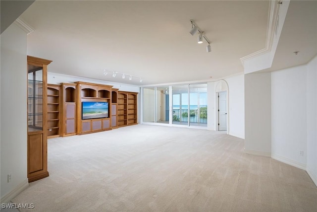 unfurnished living room featuring light carpet, track lighting, floor to ceiling windows, and ornamental molding