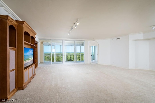 unfurnished living room featuring ceiling fan, crown molding, light carpet, a wall of windows, and rail lighting