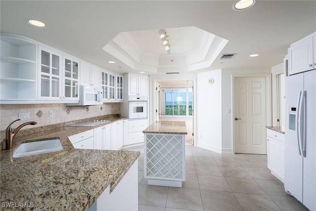 kitchen with white cabinetry, sink, a tray ceiling, and white appliances