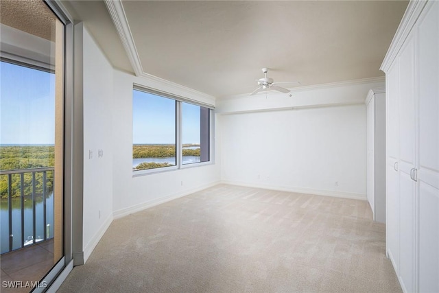 carpeted empty room with a water view, ceiling fan, and crown molding