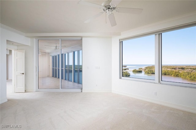 carpeted empty room featuring ceiling fan, ornamental molding, and a water view