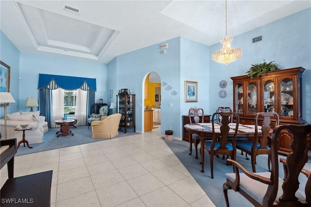 tiled dining space with an inviting chandelier, a raised ceiling, and a high ceiling