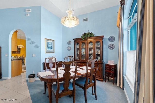 dining room featuring an inviting chandelier, a towering ceiling, and light tile patterned floors