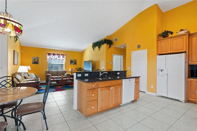 kitchen with decorative light fixtures, sink, dark stone countertops, light tile patterned floors, and white appliances