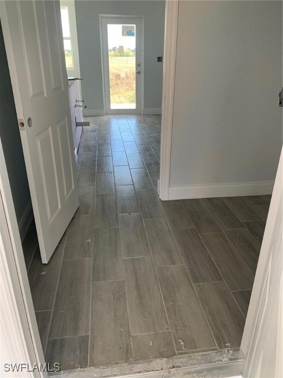 hallway with baseboards and wood tiled floor