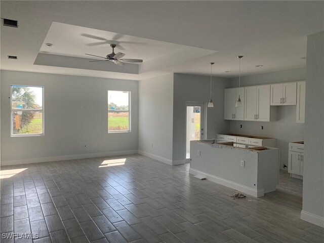 kitchen featuring visible vents, a raised ceiling, open floor plan, and wood tiled floor