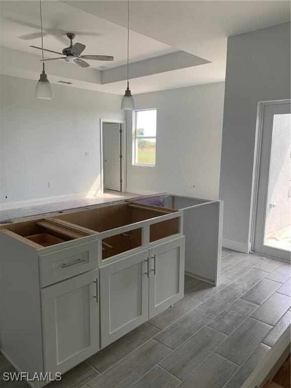 kitchen featuring a raised ceiling, pendant lighting, ceiling fan, and wood tiled floor