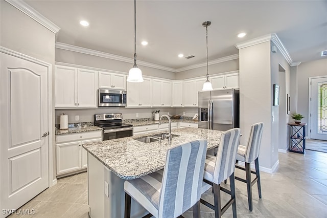 kitchen with sink, white cabinetry, hanging light fixtures, appliances with stainless steel finishes, and an island with sink