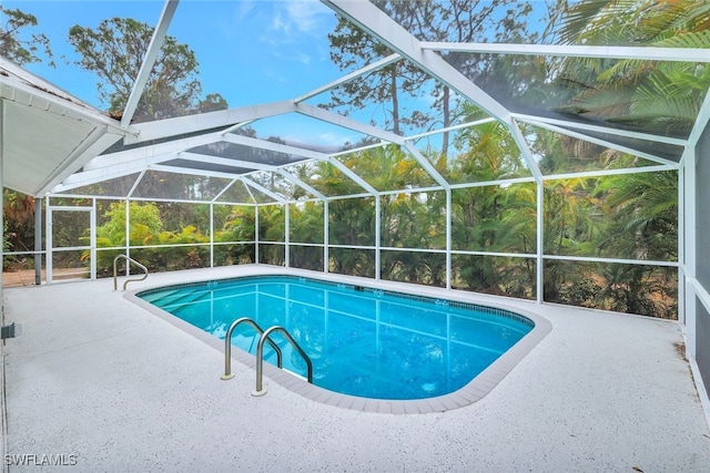 view of pool with glass enclosure and a patio