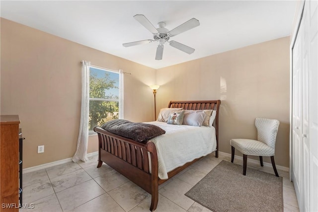 bedroom featuring ceiling fan, light tile patterned floors, and a closet