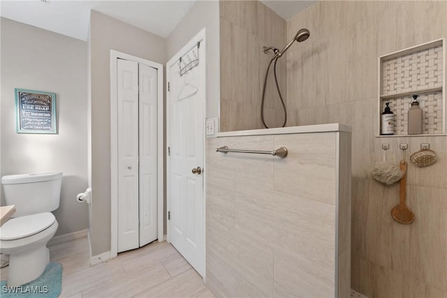 bathroom featuring tile patterned floors, toilet, and tiled shower